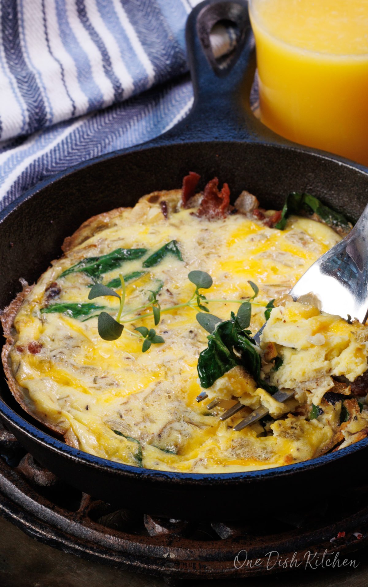 a mini frittata with a forkful of spinach and egg on the side of the skillet.