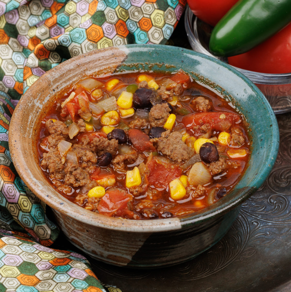a small bowl of taco soup with corn and beans next to a multi colored napkin.