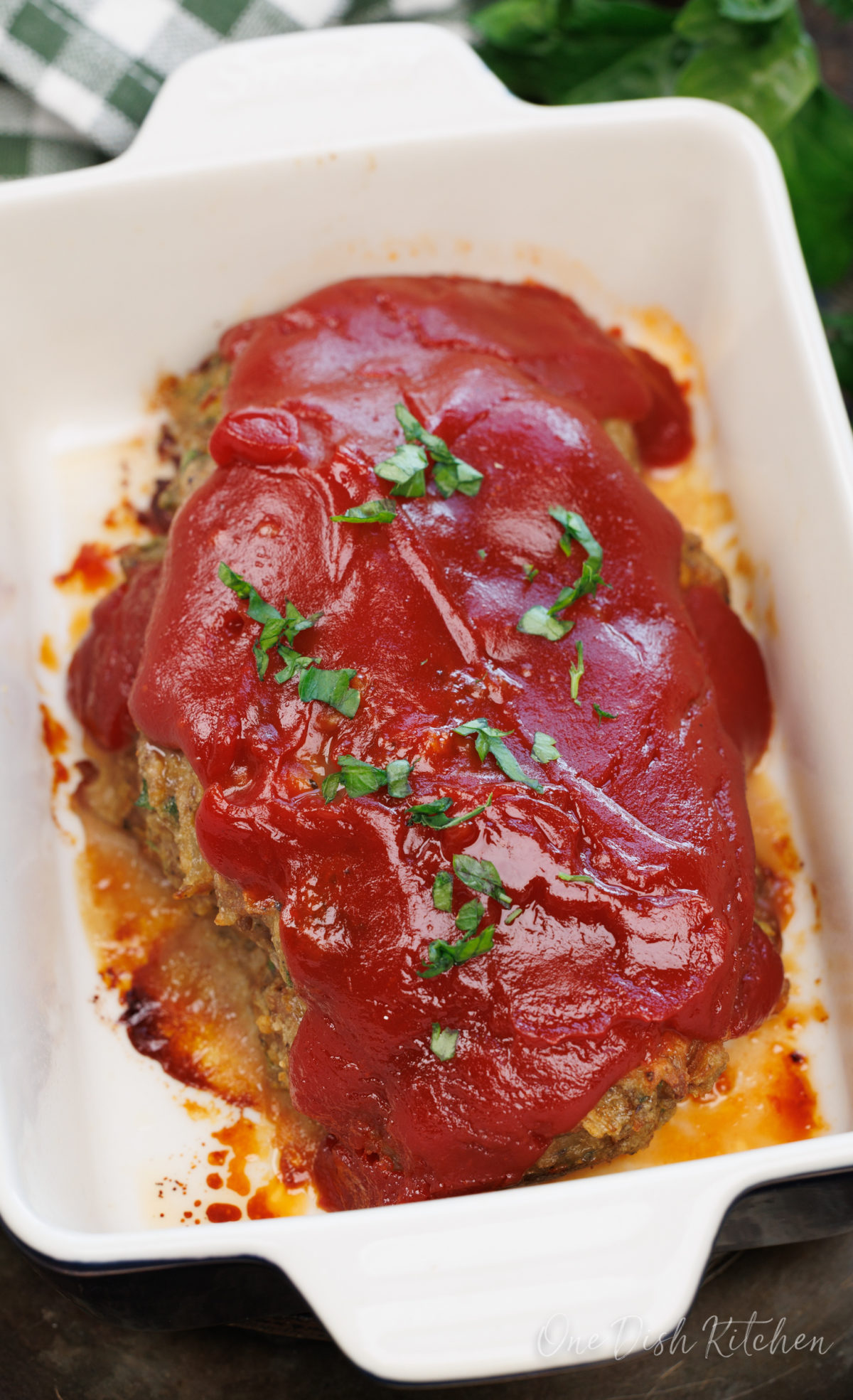 a mini turkey meatloaf topped with a tomato based glaze in a white baking dish.