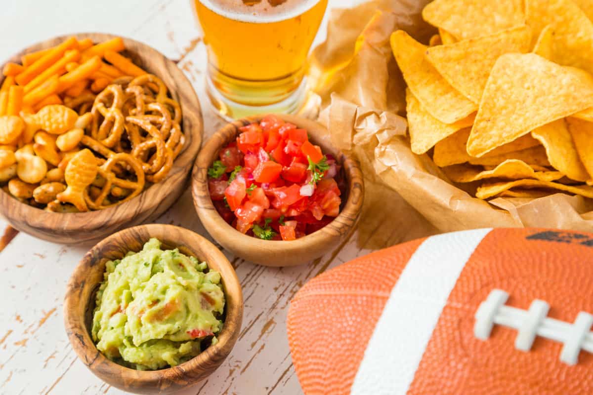 guacamole, chips, salsa, and a football on a wooden table