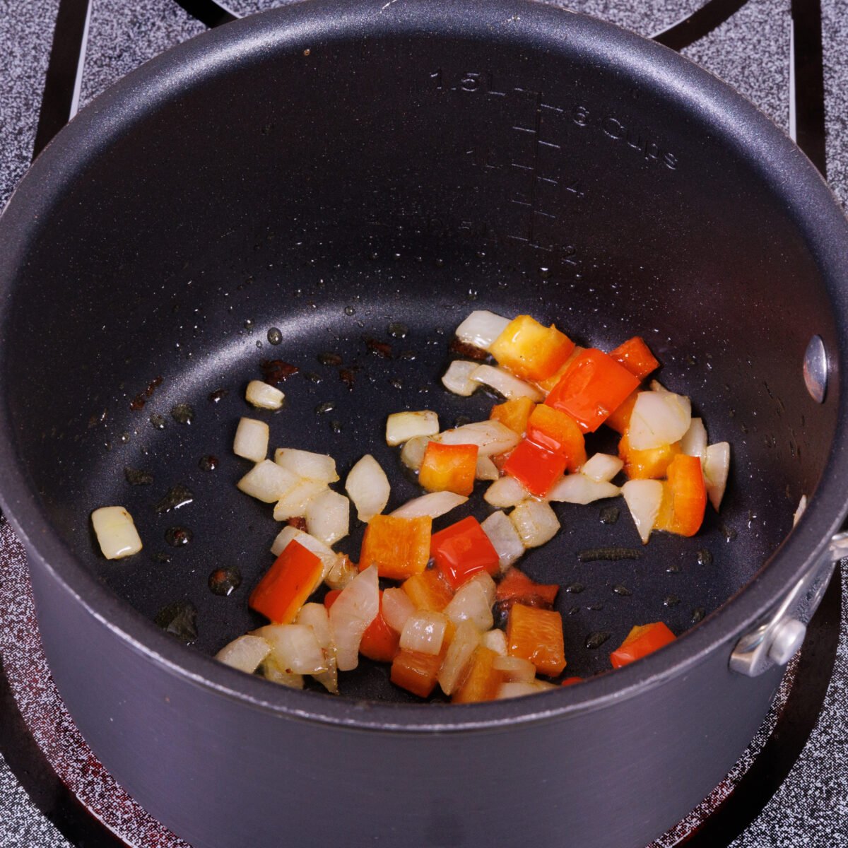 chopped onions and red peppers in a small pot.