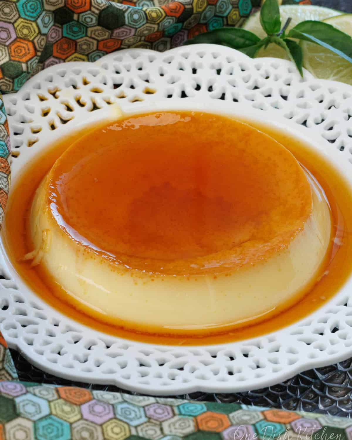 flan on a white dish next to a green and orange napkin.