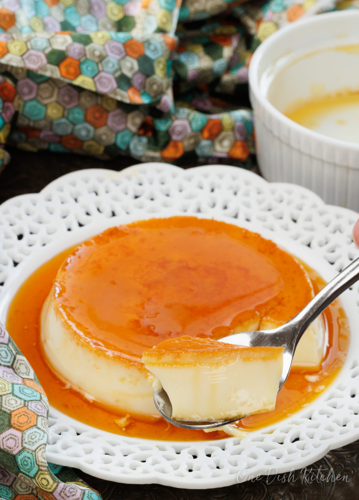a single flan on a plate with a spoon on the side.
