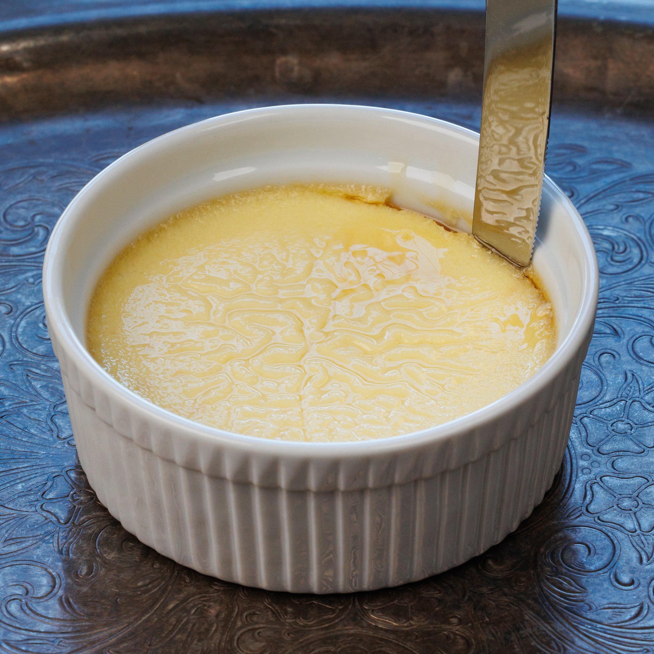 running a knife around the sides of a ramekin to unmold a flan.