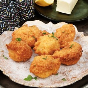a plate of hush puppies next to a plate with butter on a silver tray