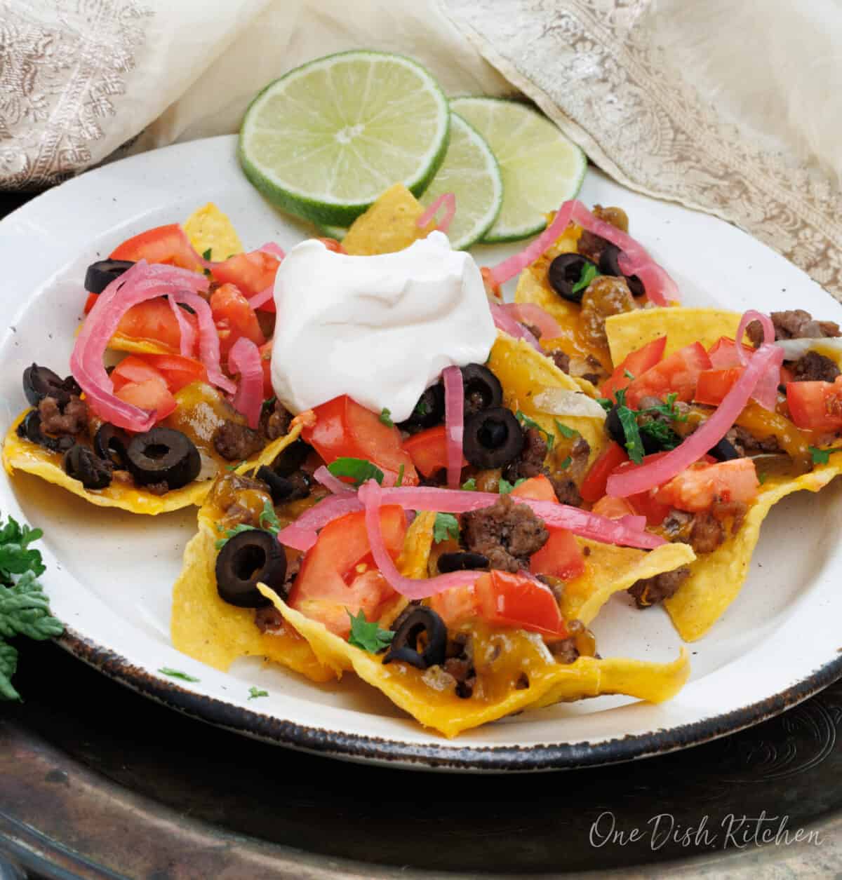 a plate of loaded nachos topped with onions and sour cream.