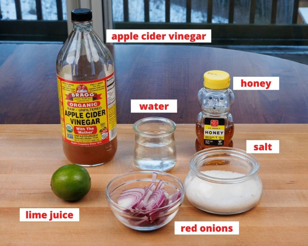 vinegar, onions, honey,lime and salt on a wooden cutting board.