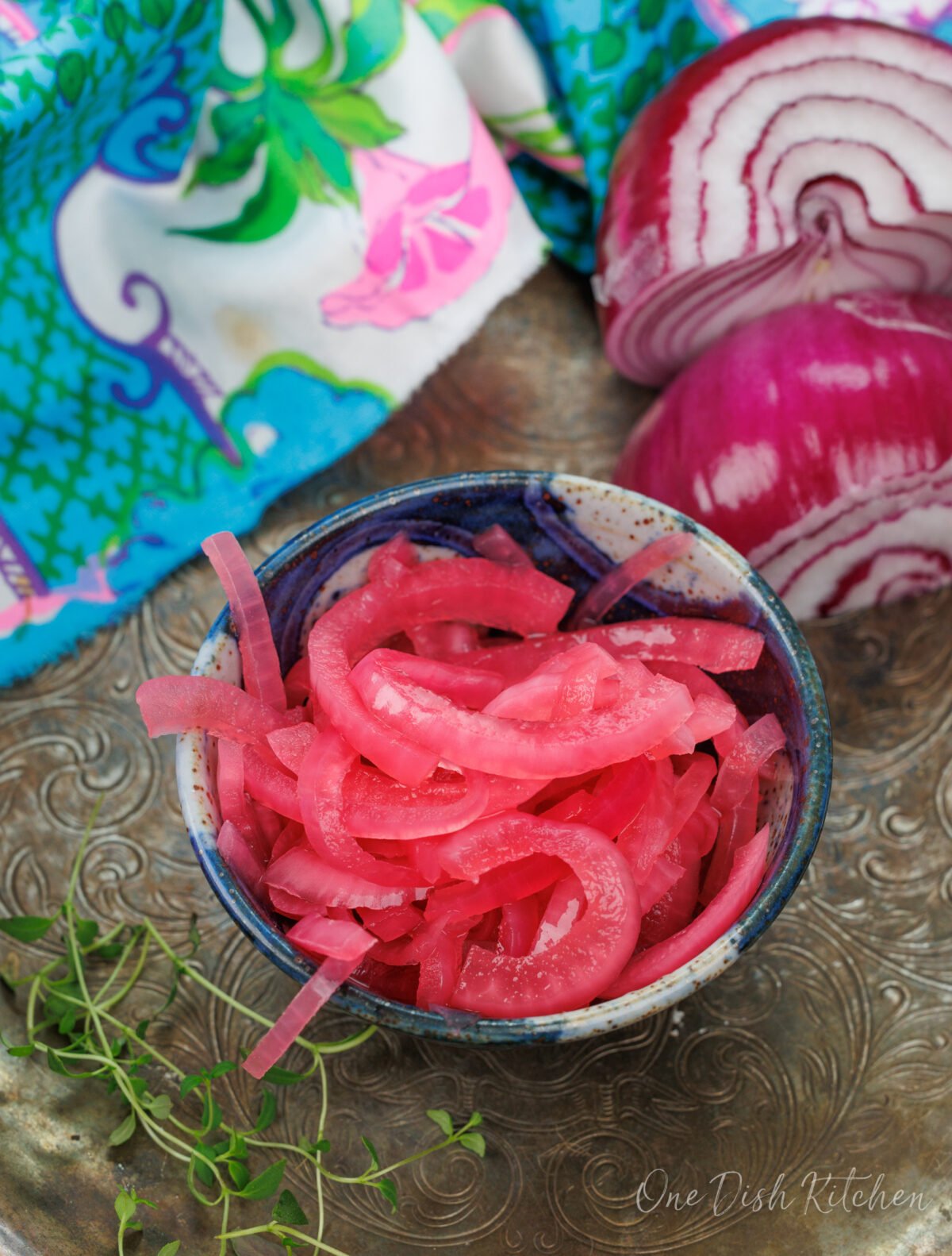 red pickled onions in a small blue bowl on a silver tray.