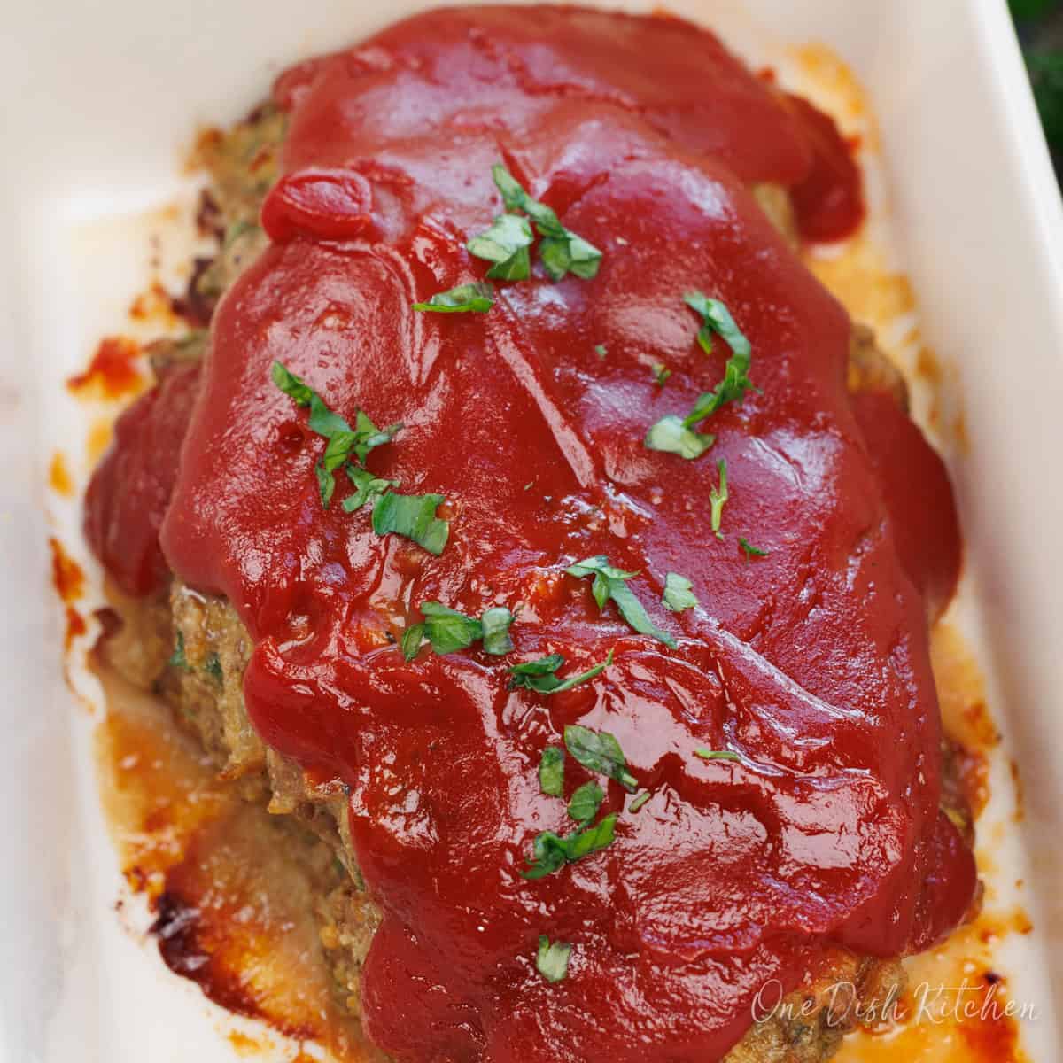 a mini meatloaf in a small baking dish on a wooden counter.