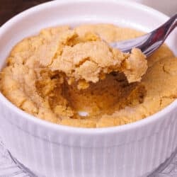 a peanut butter cookie in a small dish with a spoon on the side.