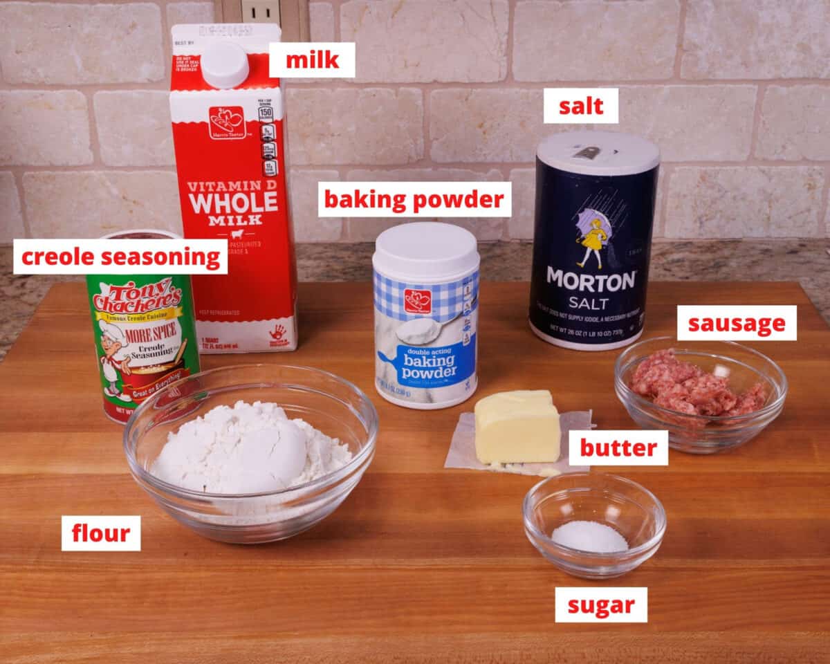 ingredients needed to make biscuits and gravy on a wooden cutting board in a kitchen.