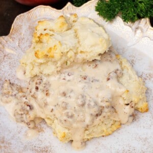 a single biscuit topped with sausage gravy on a white plate