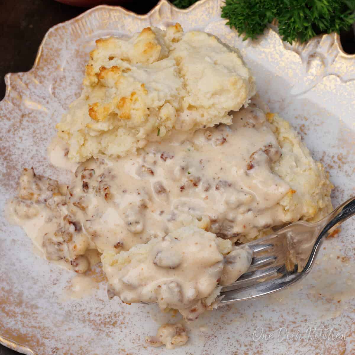 a single biscuit topped with sausage gravy on a white plate.