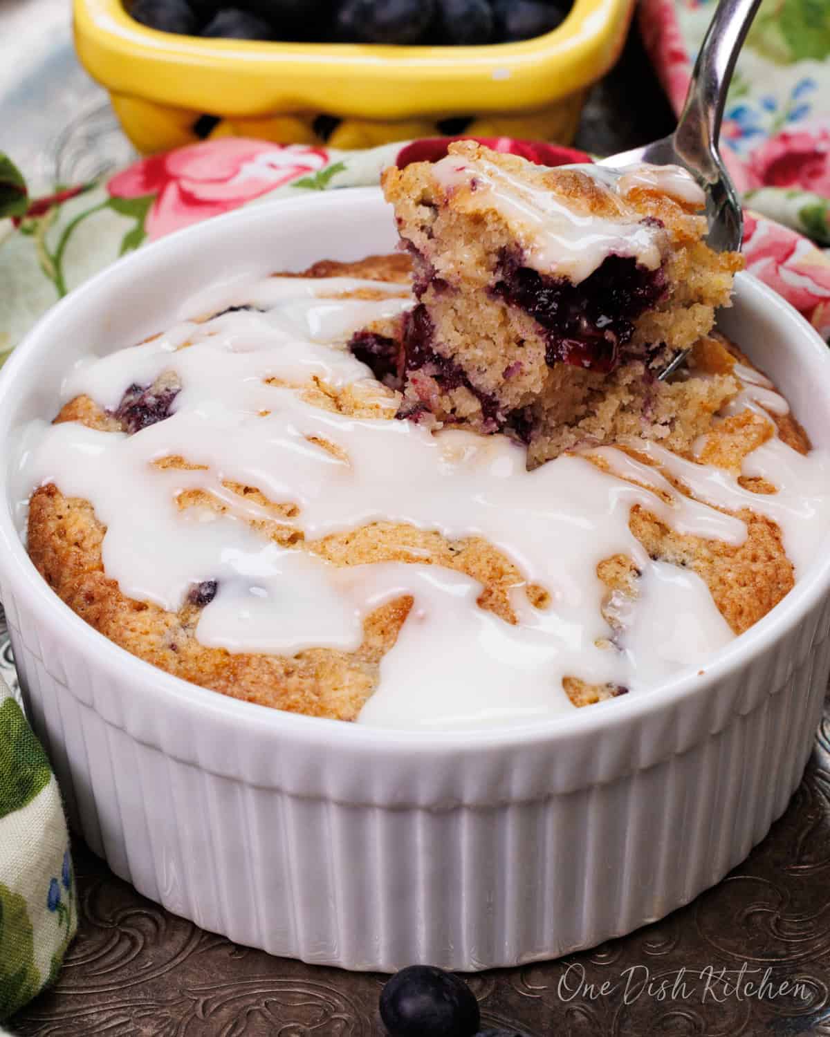 a partially eaten coffee cake with blueberries in a ramekin.
