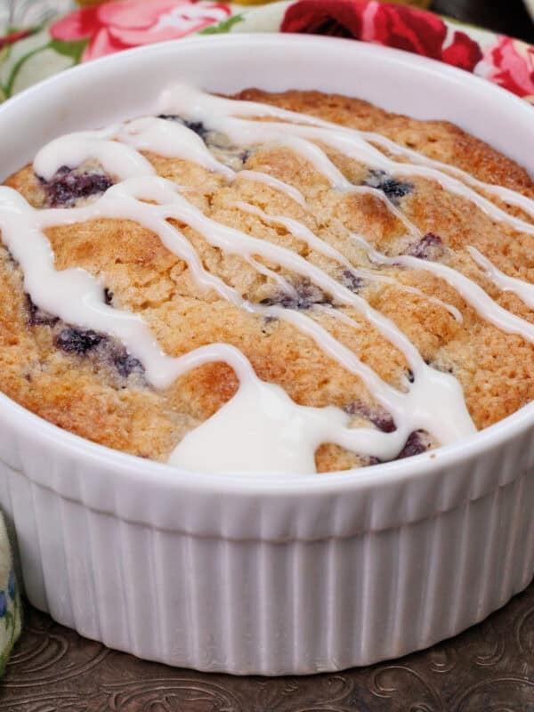a small blueberry coffee cake in a white ramekin on a silver tray.