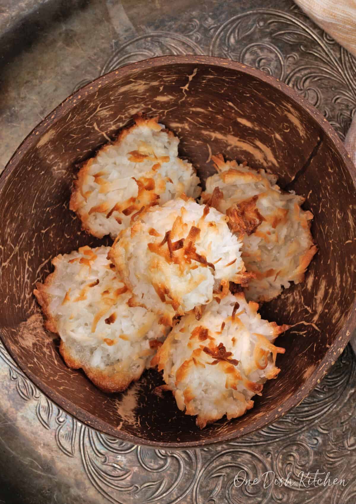 five coconut macaroons in a brown bowl.
