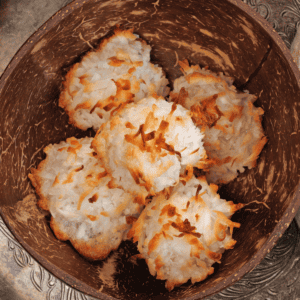 a brown coconut bowl filled with coconut macaroons.