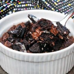 one oreo brownie in a white ramekin with a spoon on the side.
