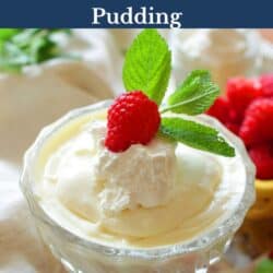 a bowl of vanilla pudding topped with whipped cream, berries, and mint.