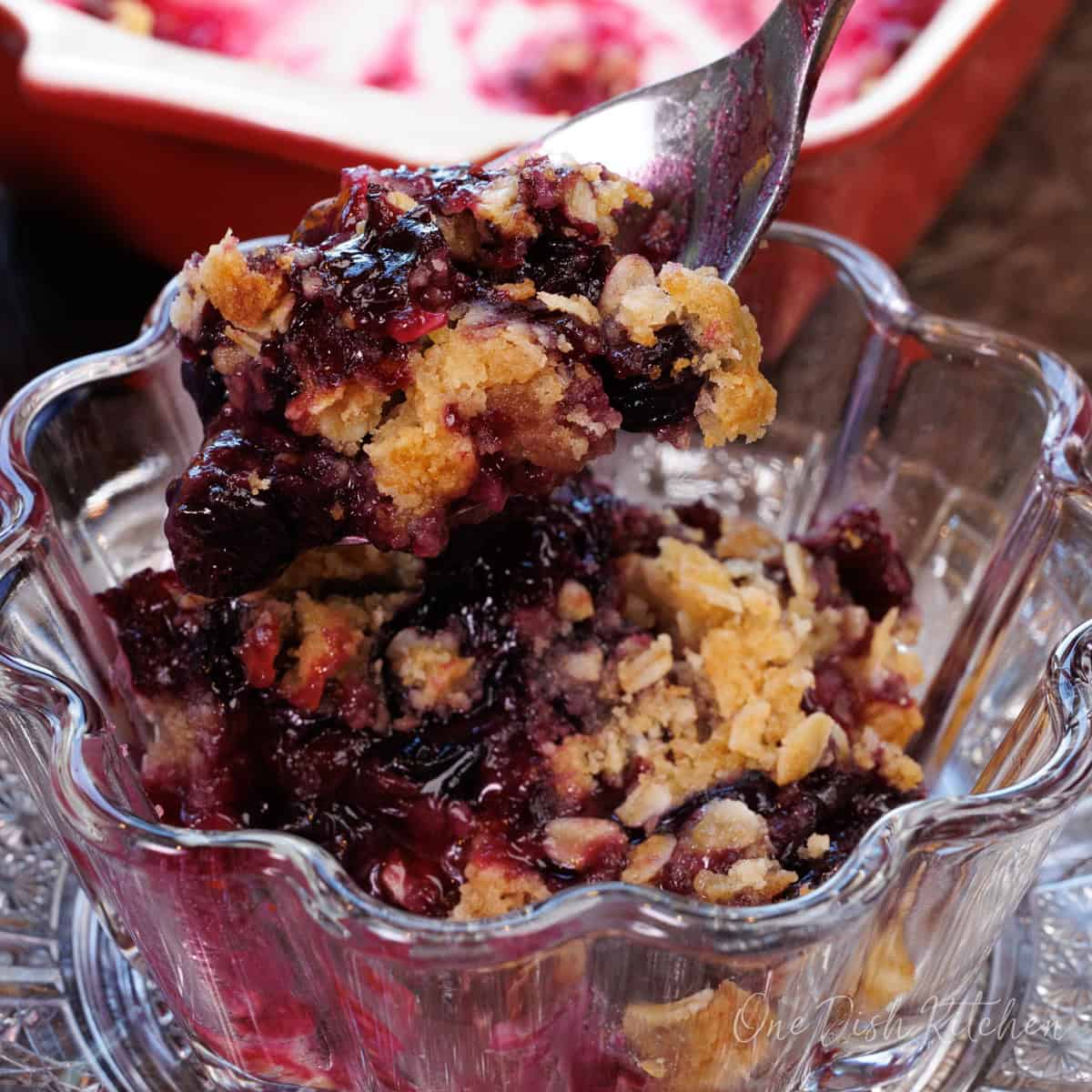 blueberry crisp in a small bowl with a spoon on the side.