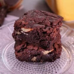 a small batch of brownies on a plate stacked on top of each other.