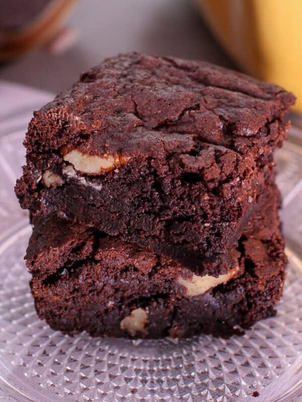 a small batch of brownies on a plate stacked on top of each other.