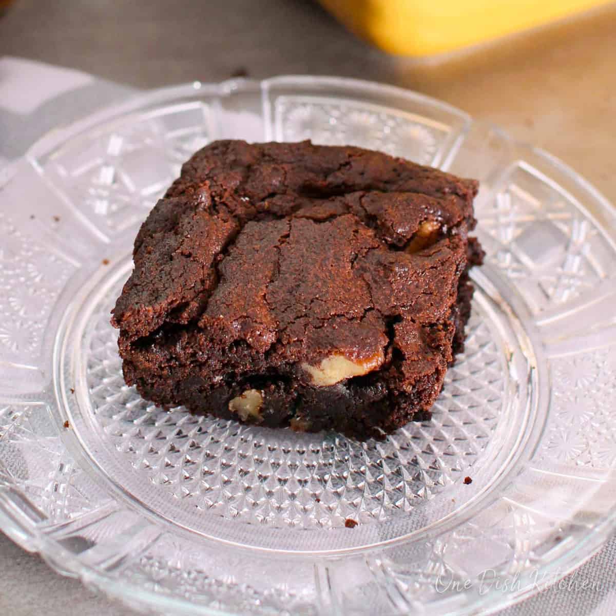 one fudge brownie with a crackly top on a white plate.