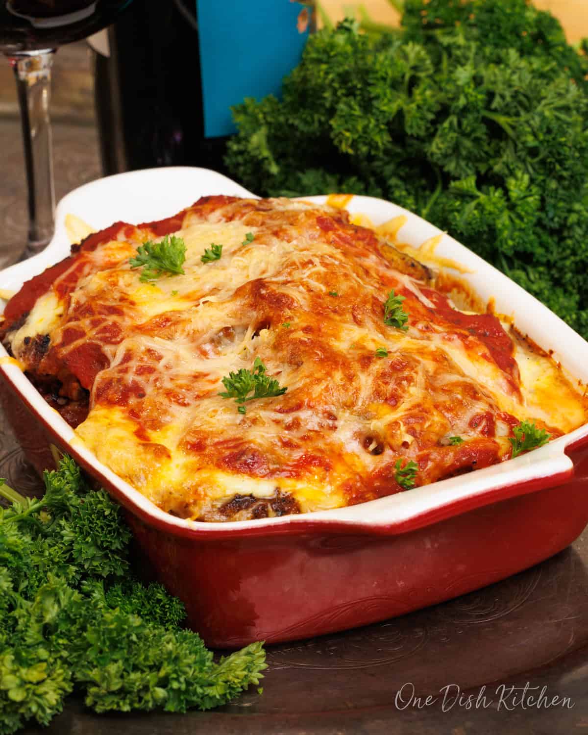 a mini eggplant parmesan in a red baking dish.
