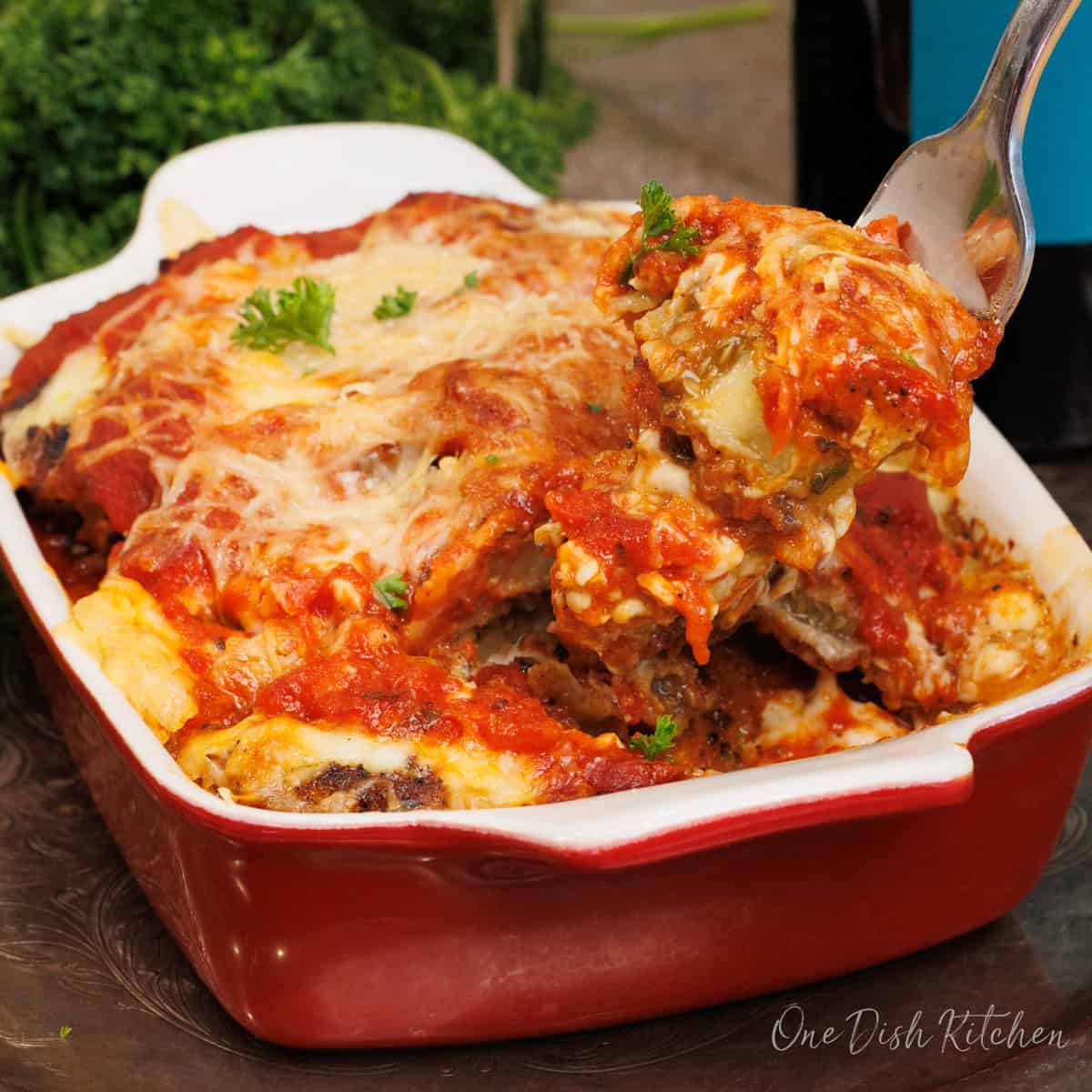 an individual eggplant parmesan in a baking dish with a fork on the side.
