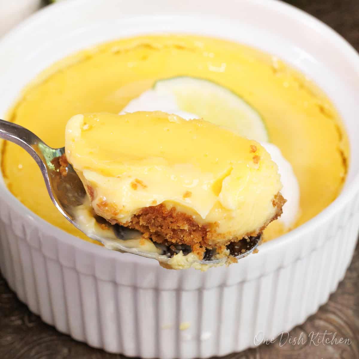 a small key lime pie in a white ramekin with a spoon on the side.