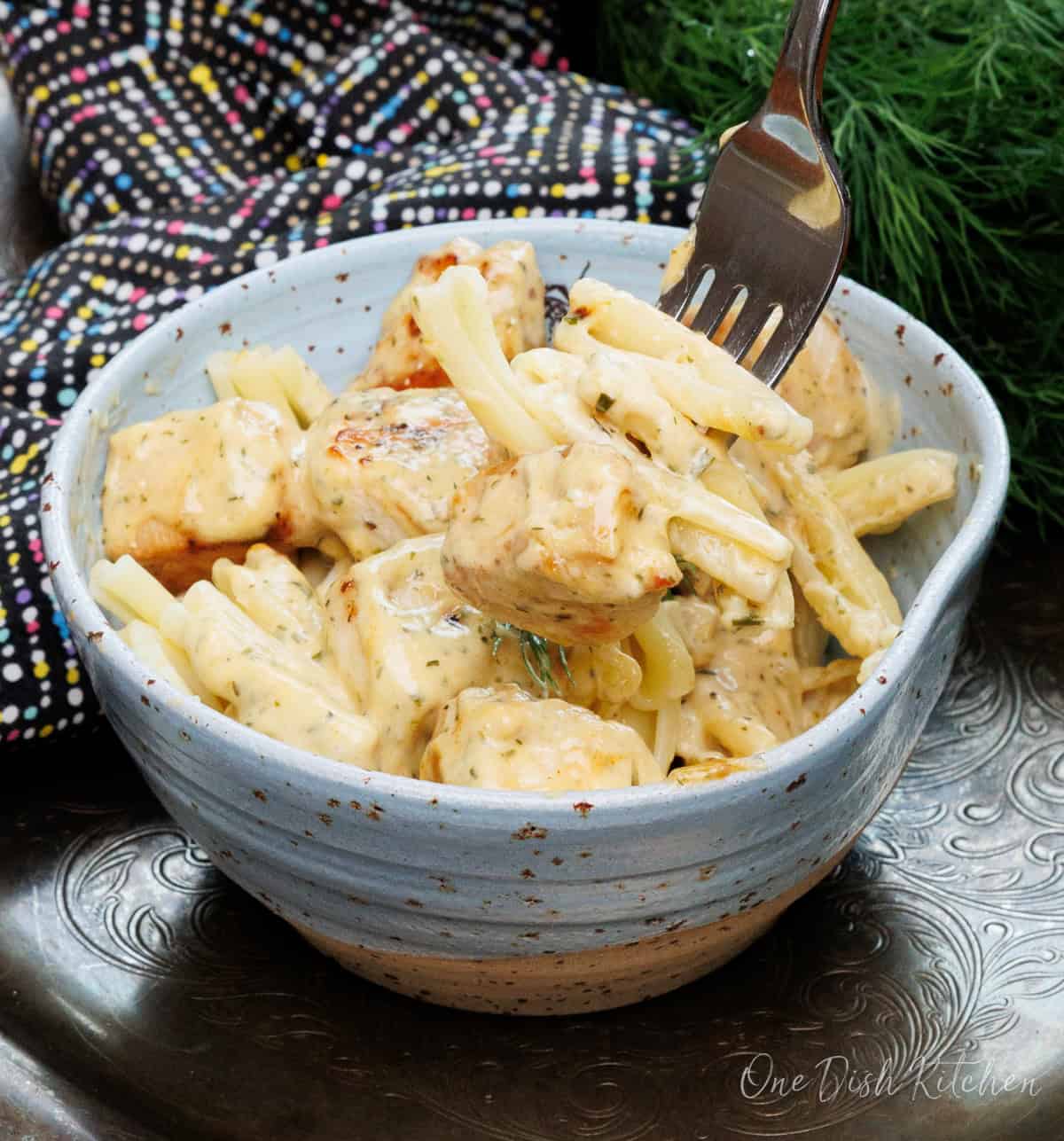 mustard chicken in a blue bowl on a silver tray.