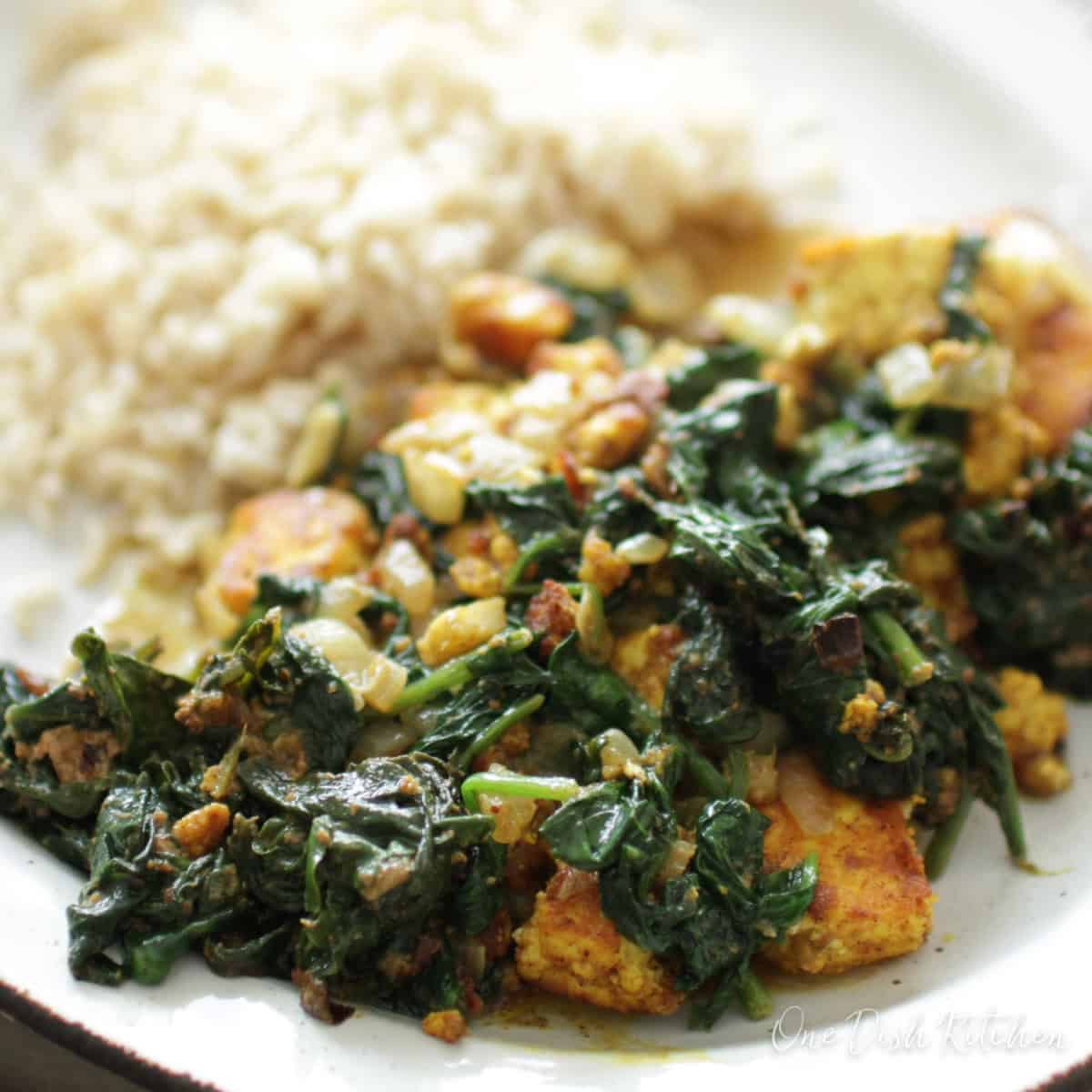 saag paneer on a white plate next to white rice.