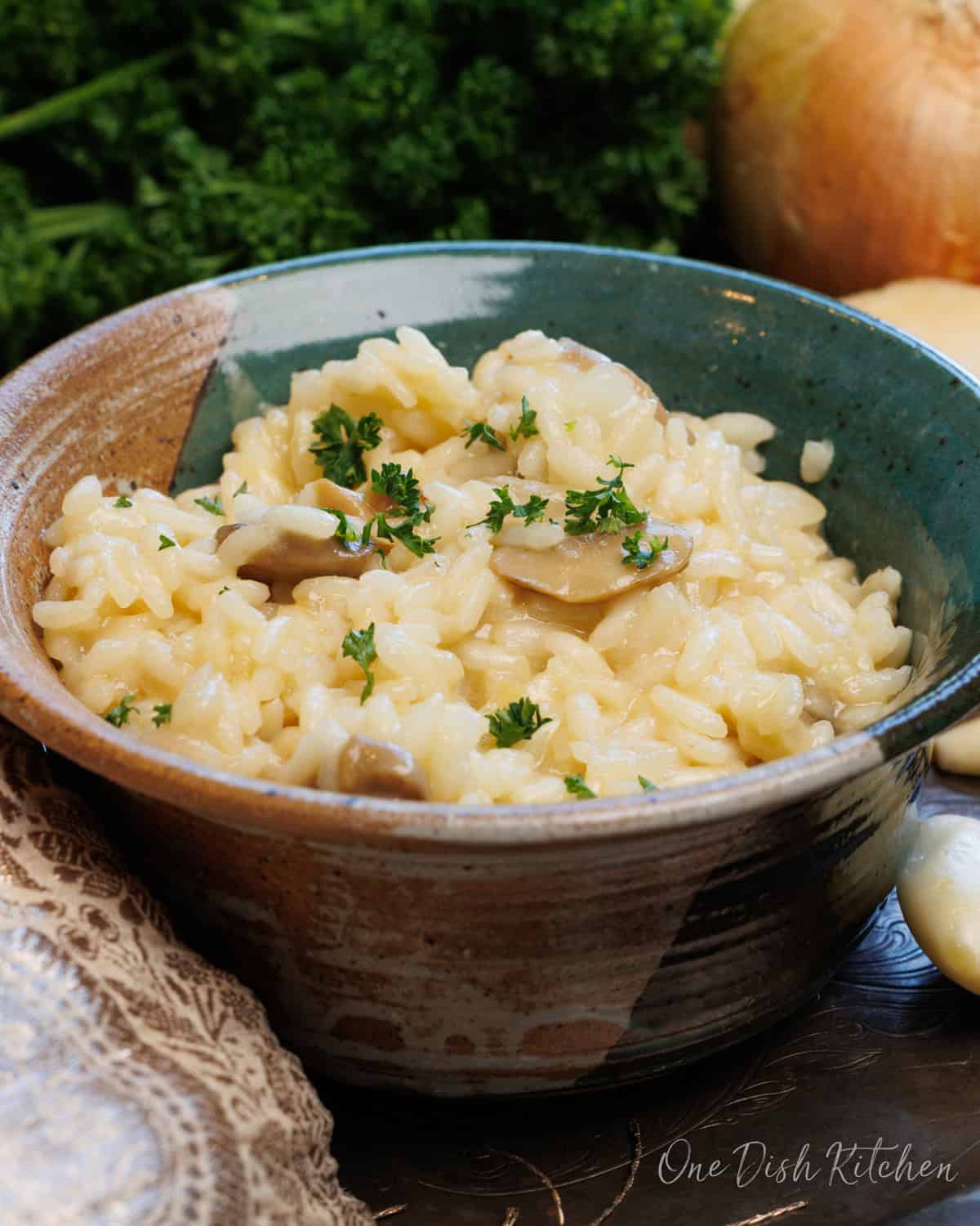a green bowl full of risotto on a silver tray.