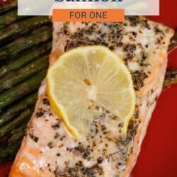 baked salmon on a red plate next to asparagus.