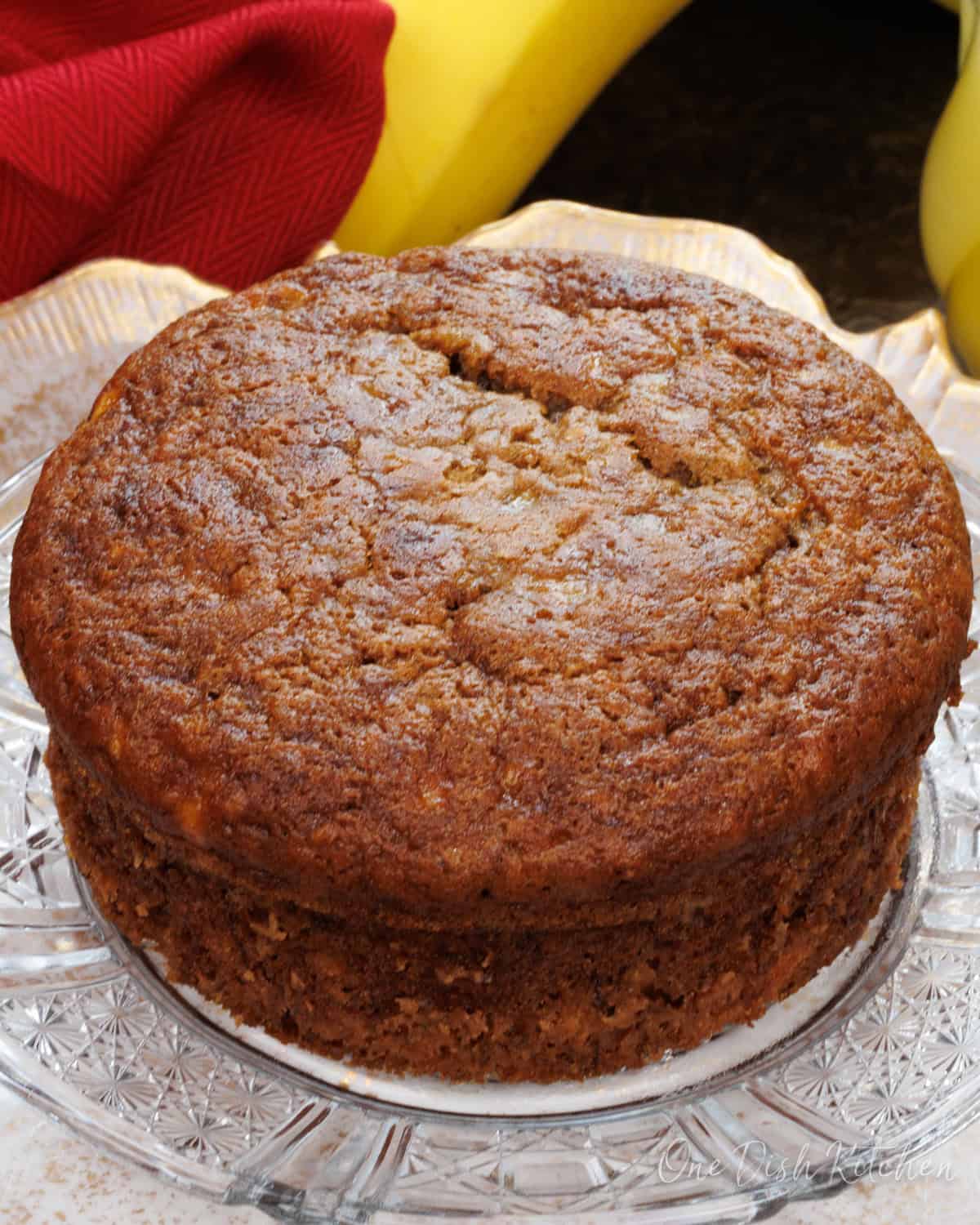 a small banana bread on a white plate next to a banana.