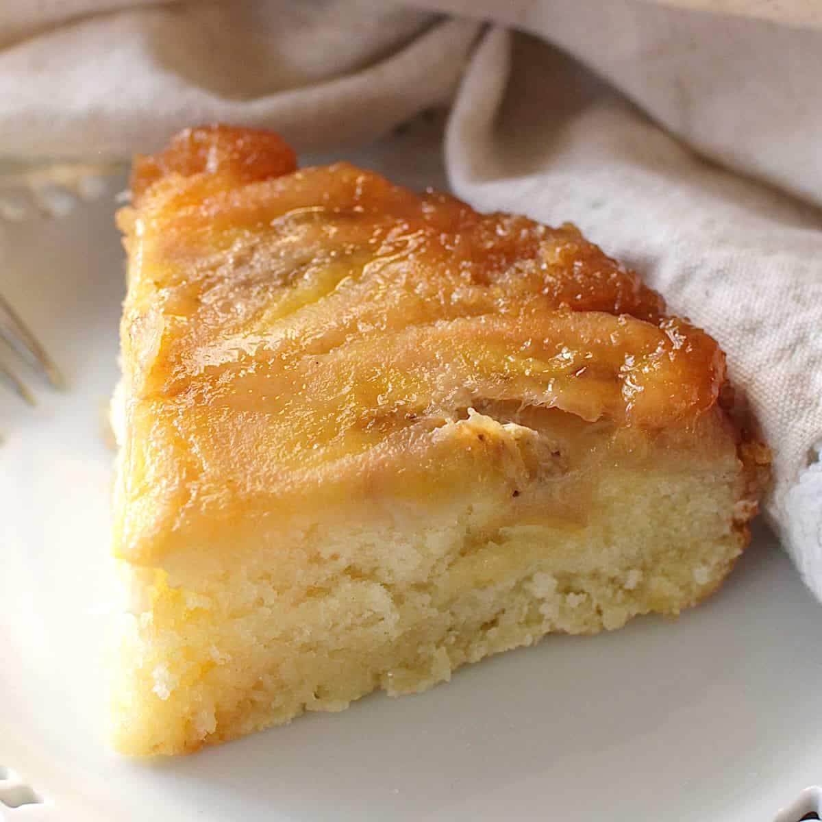 a slice of caramelized banana upside down cake on a white plate.