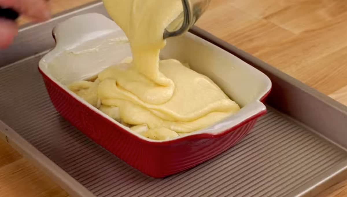 cake batter poured over sliced bananas and brown sugar in a baking dish.