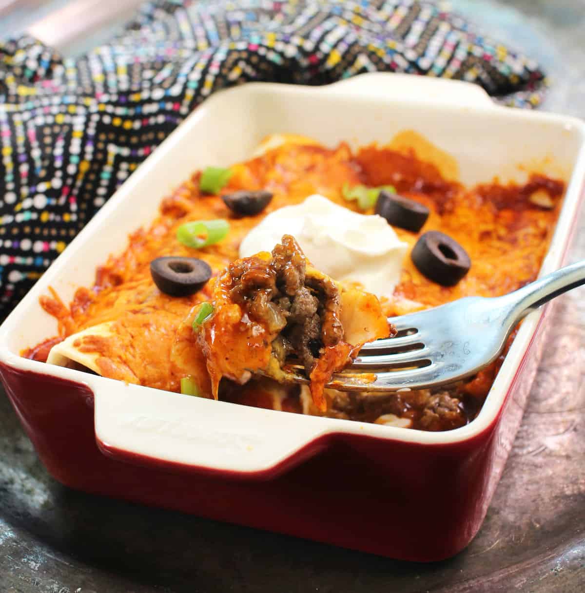 beef enchiladas in a small baking dish on a silver tray