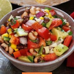 a bowl of cowboy caviar with beans and vegetables in a pink bowl.