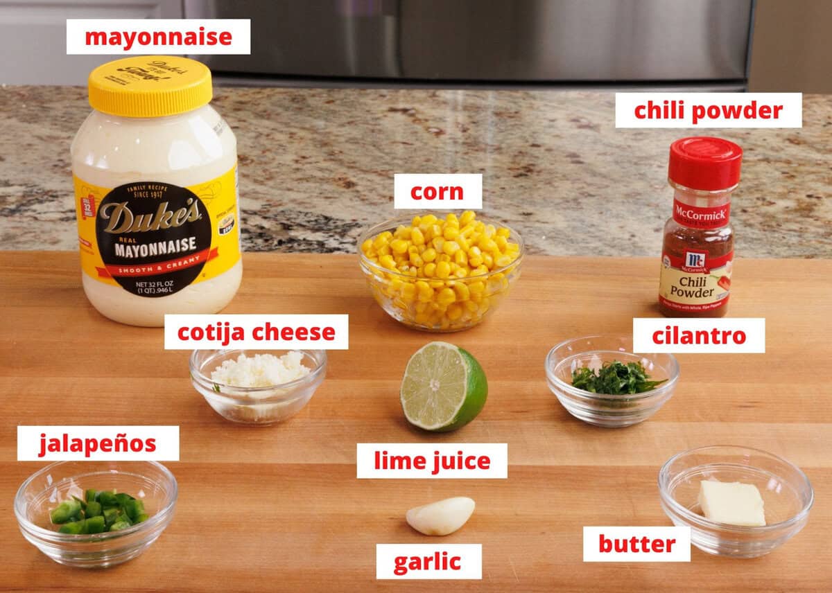 mexican street corn ingredients on a wooden cutting board in a kitchen.