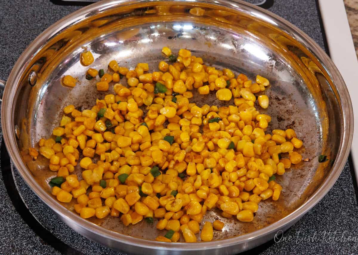 corn in a skillet with chopped jalapenos.