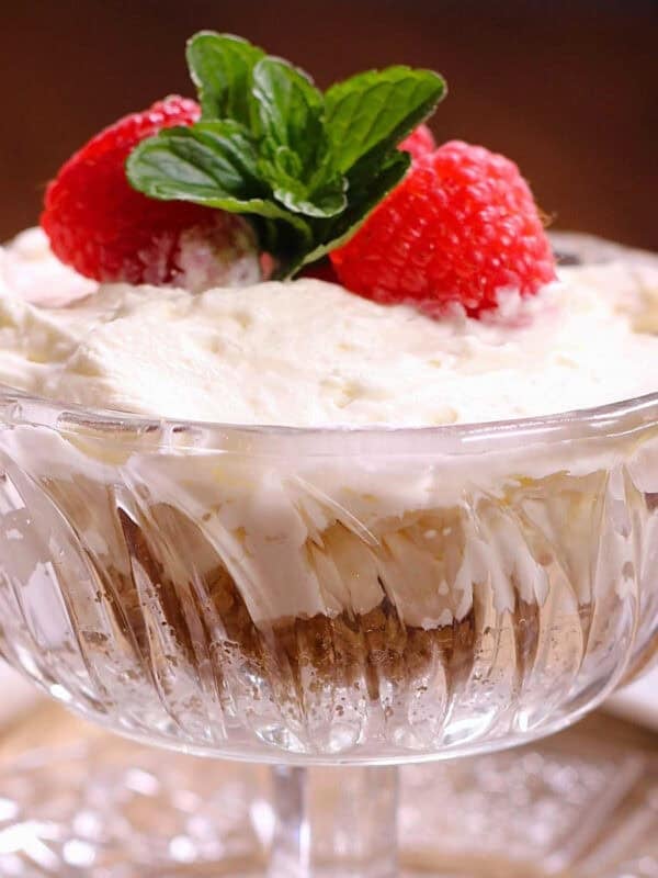 a small no bake cheesecake in a dessert dish topped with strawberries.