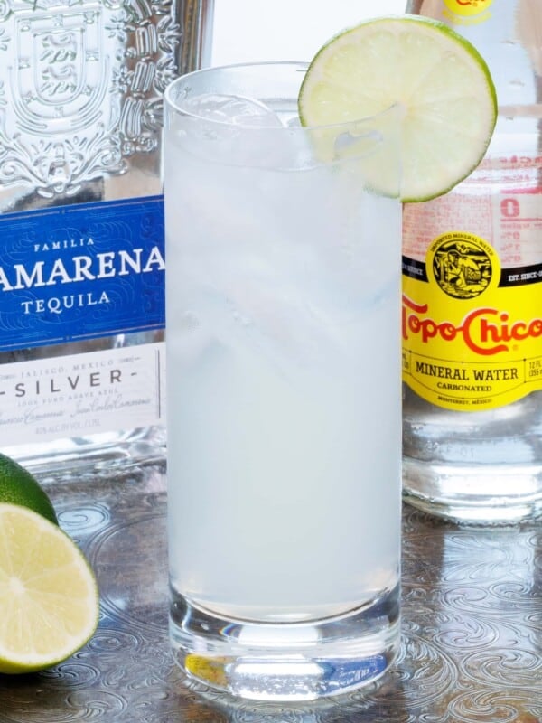 a highball glass filled with ranch water next to a lime