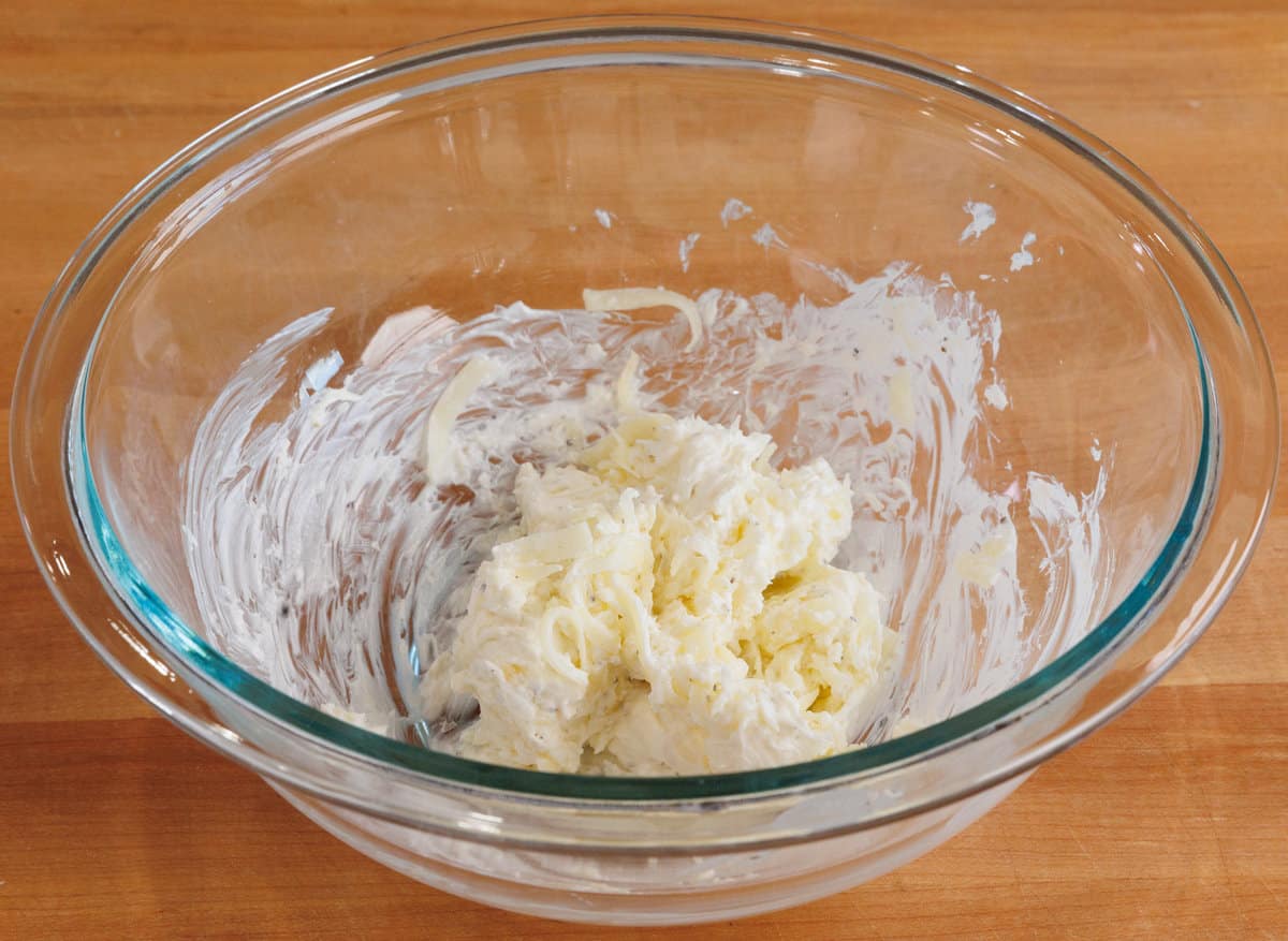 a bowl filled with cream cheese, sour cream, and cheese.