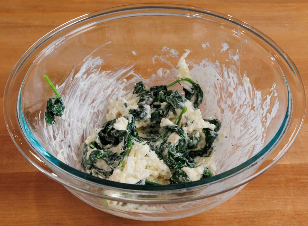 spinach dip in a bowl on a wooden table.