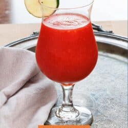 a strawberry daiquiri in a glass with a slice of lime on the rim.