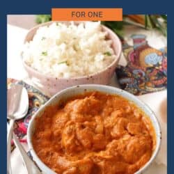 a blue bowl filled with butter chicken and butter chicken sauce next to a bowl of white rice.