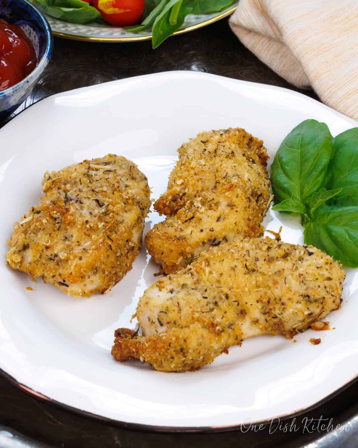 three baked chicken tenders on a white plate.