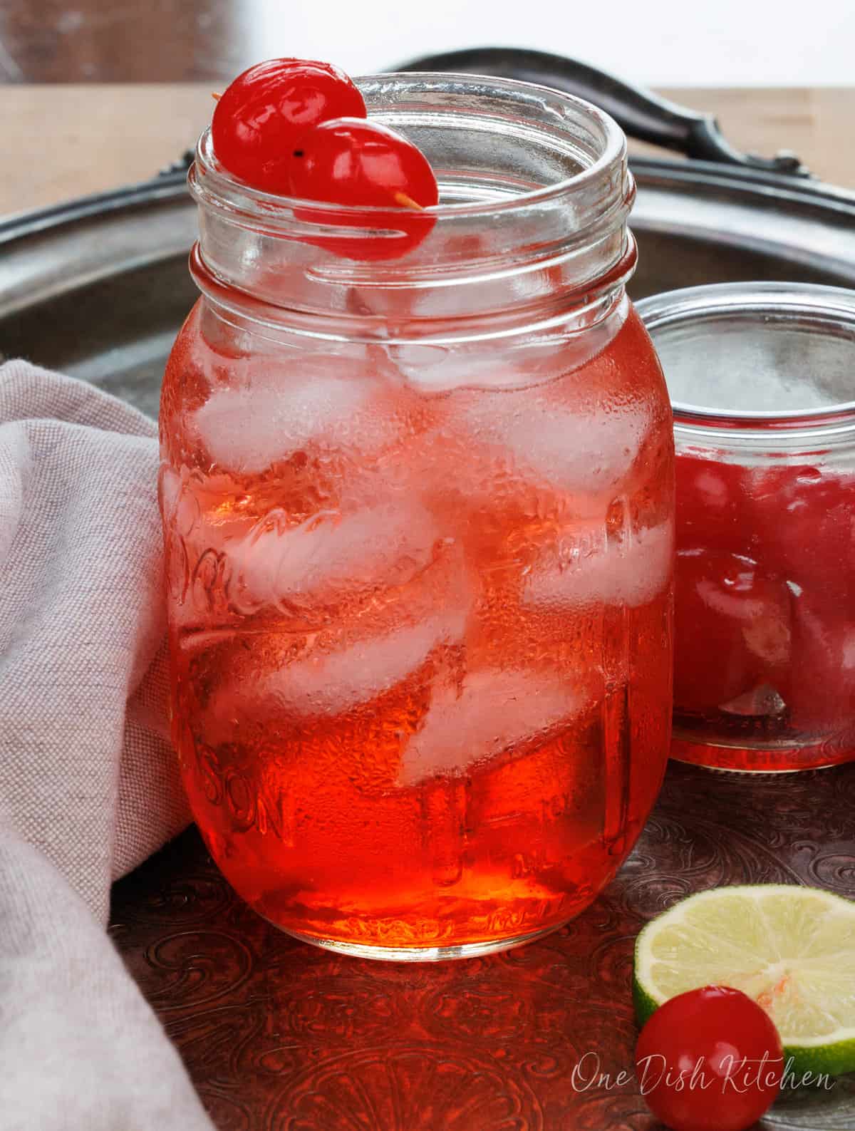 a dirty shirley on a tray next to a slice of limes and cherries