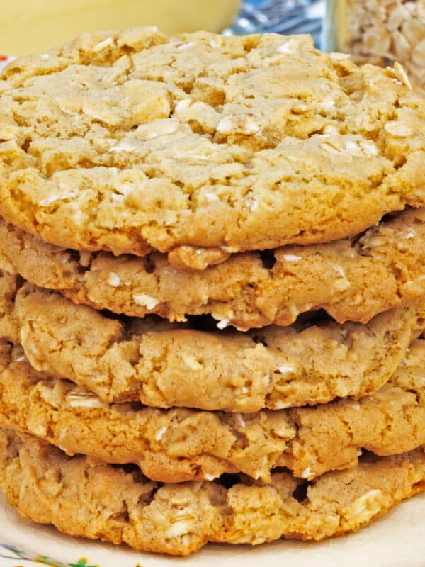 a stack of oatmeal cookies on a plate next to a stick of butter and a jar of oats.